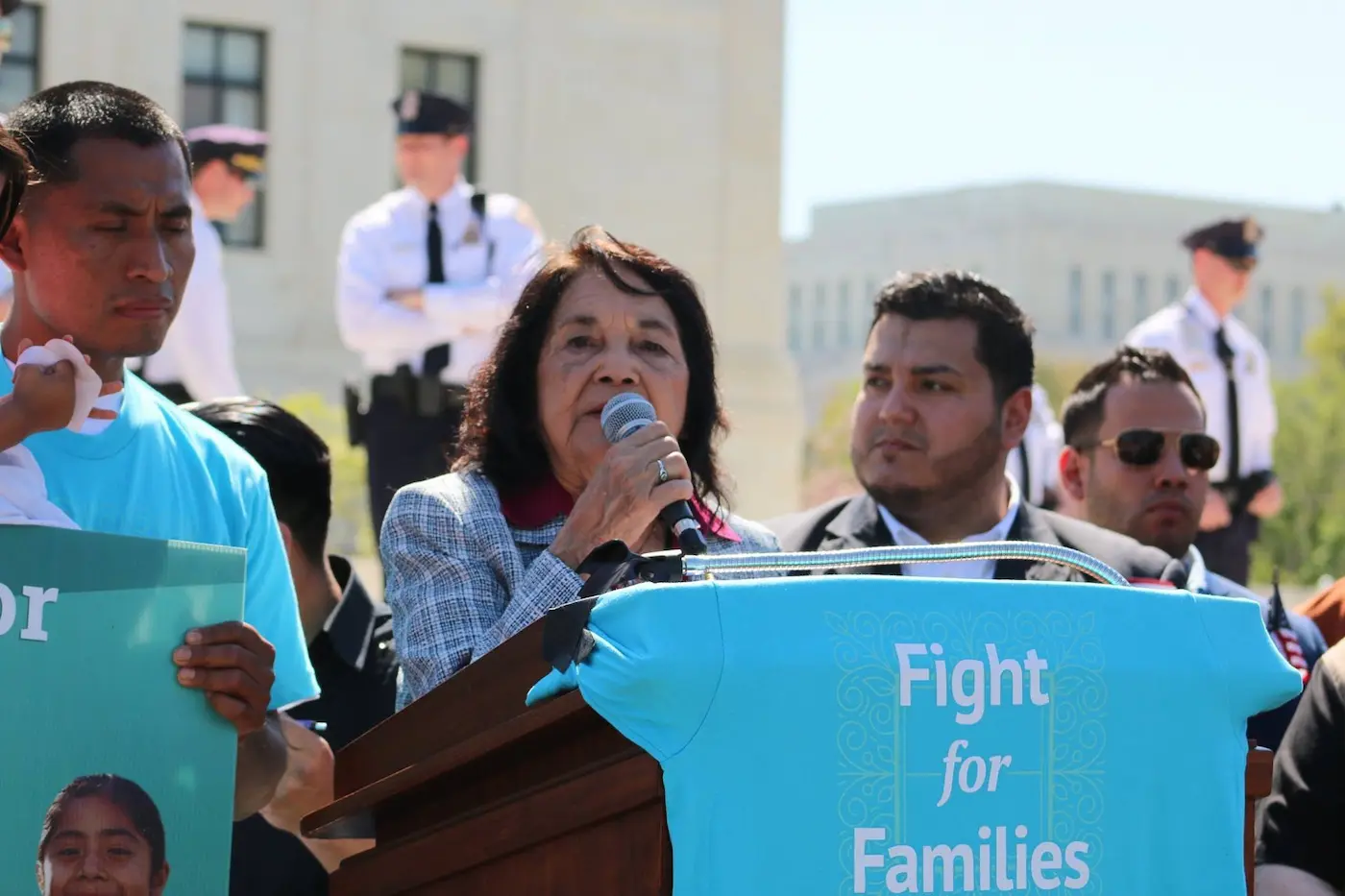 VACIR advocacy Woman speaking behind a banner that reads "Fight for Families"